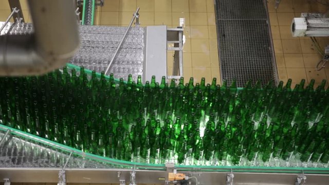 Close up of green glass unlabeled bottles of beer on bottling line 