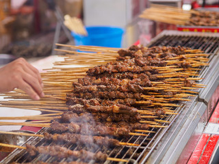 Close up of Xinjiang style lamb skewers cooking over a charcoal grill.