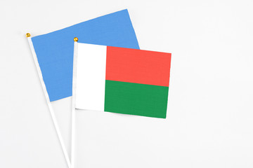 Madagascar and Somalia stick flags on white background. High quality fabric, miniature national flag. Peaceful global concept.White floor for copy space.