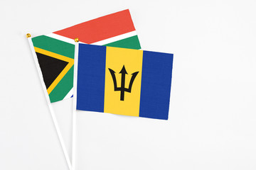 Barbados and South Africa stick flags on white background. High quality fabric, miniature national flag. Peaceful global concept.White floor for copy space.
