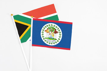 Fototapeta premium Belize and South Africa stick flags on white background. High quality fabric, miniature national flag. Peaceful global concept.White floor for copy space.