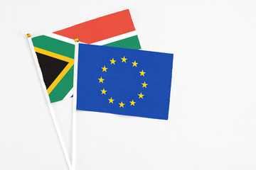 European Union and South Africa stick flags on white background. High quality fabric, miniature national flag. Peaceful global concept.White floor for copy space.