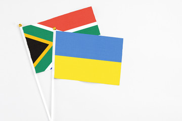 Ukraine and South Africa stick flags on white background. High quality fabric, miniature national flag. Peaceful global concept.White floor for copy space.