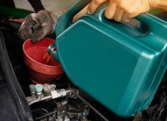 Car maintenance concept.Car mechanic replacing and pouring fresh oil into engine at maintenance...