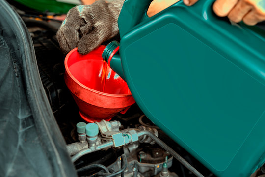 Car maintenance concept.Car mechanic replacing and pouring fresh oil into engine at maintenance service station.Auto repair technician pour new engine oil to replace the old one
