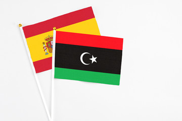 Libya and Spain stick flags on white background. High quality fabric, miniature national flag. Peaceful global concept.White floor for copy space.