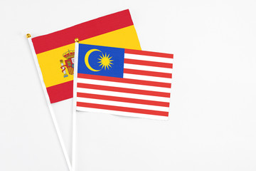 Malaysia and Spain stick flags on white background. High quality fabric, miniature national flag. Peaceful global concept.White floor for copy space.