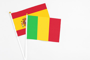 Mali and Spain stick flags on white background. High quality fabric, miniature national flag. Peaceful global concept.White floor for copy space.