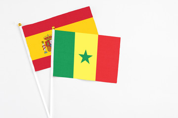 Fototapeta premium Senegal and Spain stick flags on white background. High quality fabric, miniature national flag. Peaceful global concept.White floor for copy space.