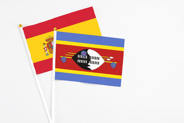 Swaziland and Spain stick flags on white background. High quality fabric, miniature national flag. Peaceful global concept.White floor for copy space.