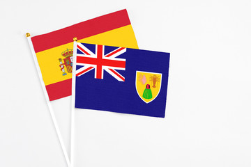 Turks And Caicos Islands and Spain stick flags on white background. High quality fabric, miniature national flag. Peaceful global concept.White floor for copy space.