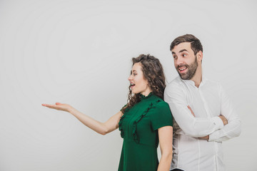 Copyspace shot of couple presenting something over white background and looking at it shocked and...