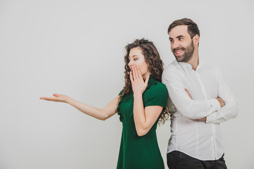 Copyspace shot of couple presenting something over white background and looking at it shocked and amazed.
