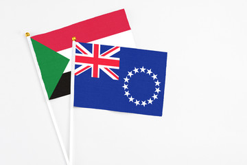 Cook Islands and Sudan stick flags on white background. High quality fabric, miniature national flag. Peaceful global concept.White floor for copy space.