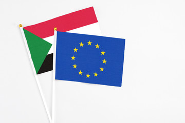 European Union and Sudan stick flags on white background. High quality fabric, miniature national flag. Peaceful global concept.White floor for copy space.