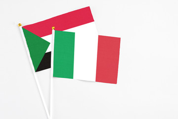 Italy and Sudan stick flags on white background. High quality fabric, miniature national flag. Peaceful global concept.White floor for copy space.