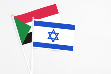Israel and Sudan stick flags on white background. High quality fabric, miniature national flag. Peaceful global concept.White floor for copy space.