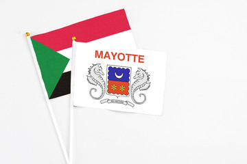 Mayotte and Sudan stick flags on white background. High quality fabric, miniature national flag. Peaceful global concept.White floor for copy space.