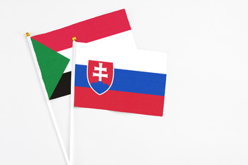 Slovakia and Sudan stick flags on white background. High quality fabric, miniature national flag. Peaceful global concept.White floor for copy space.