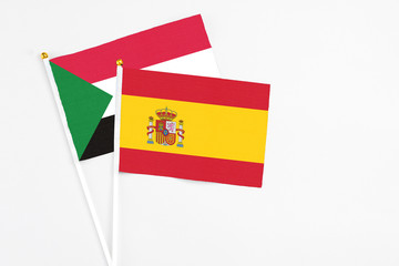 Spain and Sudan stick flags on white background. High quality fabric, miniature national flag. Peaceful global concept.White floor for copy space.