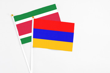 Armenia and Suriname stick flags on white background. High quality fabric, miniature national flag. Peaceful global concept.White floor for copy space.
