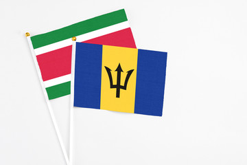 Barbados and Suriname stick flags on white background. High quality fabric, miniature national flag. Peaceful global concept.White floor for copy space.