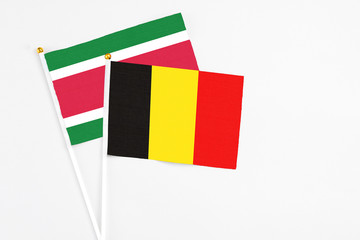 Belgium and Suriname stick flags on white background. High quality fabric, miniature national flag. Peaceful global concept.White floor for copy space.