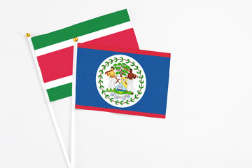 Belize and Suriname stick flags on white background. High quality fabric, miniature national flag. Peaceful global concept.White floor for copy space.
