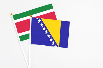 Bosnia Herzegovina and Suriname stick flags on white background. High quality fabric, miniature...