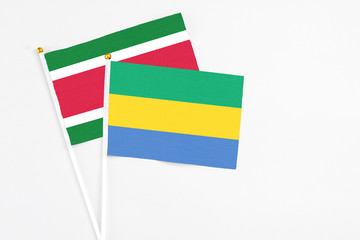 Gabon and Suriname stick flags on white background. High quality fabric, miniature national flag....