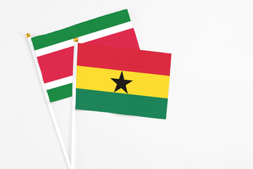 Ghana and Suriname stick flags on white background. High quality fabric, miniature national flag. Peaceful global concept.White floor for copy space.