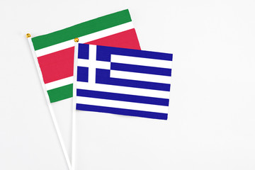 Greece and Suriname stick flags on white background. High quality fabric, miniature national flag. Peaceful global concept.White floor for copy space.