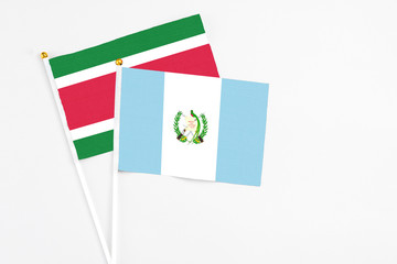 Guatemala and Suriname stick flags on white background. High quality fabric, miniature national flag. Peaceful global concept.White floor for copy space.