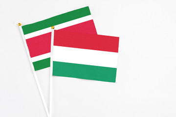 Hungary and Suriname stick flags on white background. High quality fabric, miniature national flag. Peaceful global concept.White floor for copy space.