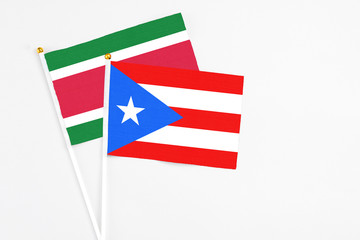 Puerto Rico and Suriname stick flags on white background. High quality fabric, miniature national flag. Peaceful global concept.White floor for copy space.