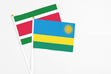 Rwanda and Suriname stick flags on white background. High quality fabric, miniature national flag. Peaceful global concept.White floor for copy space.