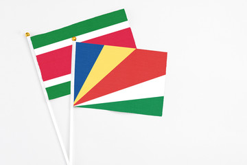Seychelles and Suriname stick flags on white background. High quality fabric, miniature national flag. Peaceful global concept.White floor for copy space.