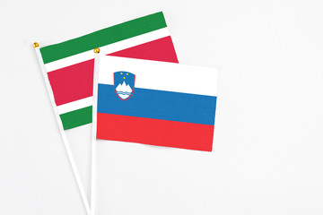 Slovenia and Suriname stick flags on white background. High quality fabric, miniature national flag. Peaceful global concept.White floor for copy space.