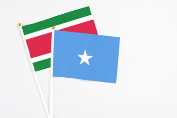 Somalia and Suriname stick flags on white background. High quality fabric, miniature national flag. Peaceful global concept.White floor for copy space.