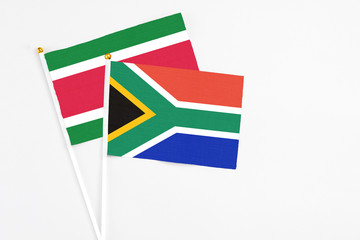 South Africa and Suriname stick flags on white background. High quality fabric, miniature national flag. Peaceful global concept.White floor for copy space.