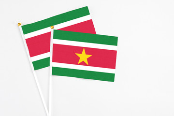 Suriname and Suriname stick flags on white background. High quality fabric, miniature national flag. Peaceful global concept.White floor for copy space.