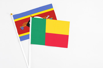 Benin and Swaziland stick flags on white background. High quality fabric, miniature national flag. Peaceful global concept.White floor for copy space.