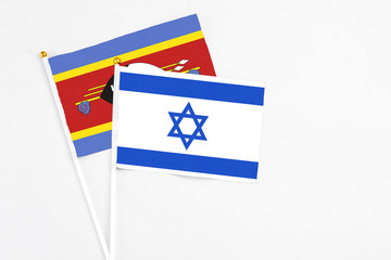 Israel and Swaziland stick flags on white background. High quality fabric, miniature national flag. Peaceful global concept.White floor for copy space.