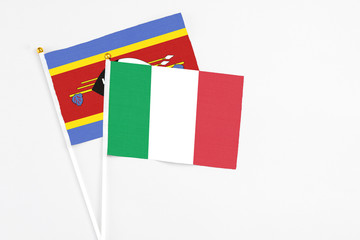 Italy and Swaziland stick flags on white background. High quality fabric, miniature national flag. Peaceful global concept.White floor for copy space.