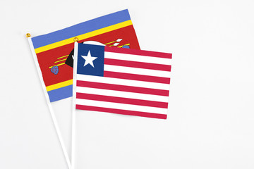 Liberia and Swaziland stick flags on white background. High quality fabric, miniature national flag. Peaceful global concept.White floor for copy space.
