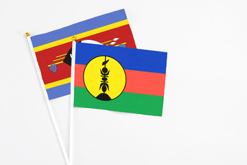 New Caledonia and Swaziland stick flags on white background. High quality fabric, miniature national flag. Peaceful global concept.White floor for copy space.