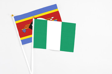 Fototapeta premium Nigeria and Swaziland stick flags on white background. High quality fabric, miniature national flag. Peaceful global concept.White floor for copy space.