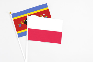 Poland and Swaziland stick flags on white background. High quality fabric, miniature national flag. Peaceful global concept.White floor for copy space.