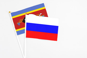 Russia and Swaziland stick flags on white background. High quality fabric, miniature national flag. Peaceful global concept.White floor for copy space.