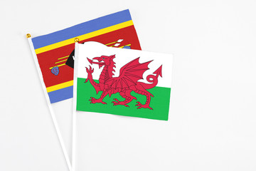 Wales and Swaziland stick flags on white background. High quality fabric, miniature national flag. Peaceful global concept.White floor for copy space.